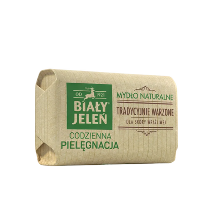 Bar of soap in a brown paper wrap with green text on a light gray background